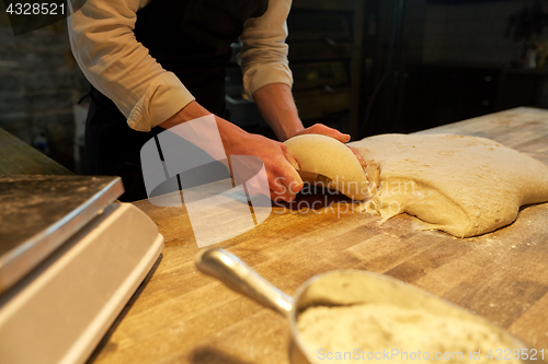 Image of baker portioning dough with bench cutter at bakery