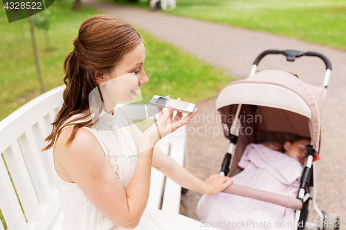 Image of mother with stroller and smartphone at summer park