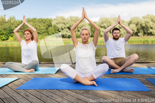 Image of people meditating in yoga lotus pose outdoors