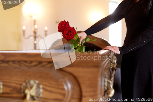 Image of woman with red roses and coffin at funeral