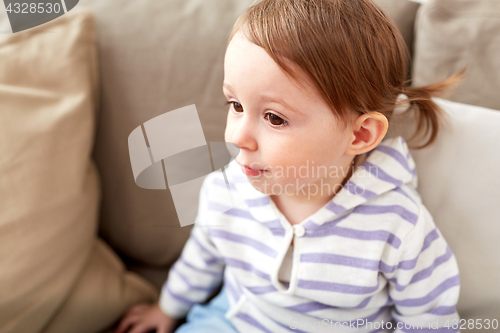 Image of close up of baby girl sitting on sofa at home
