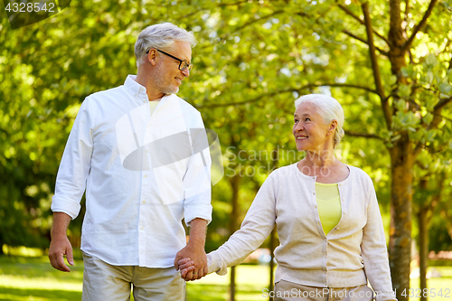 Image of happy senior couple walking at summer park