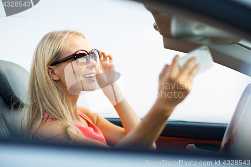 Image of woman in convertible car taking selfie