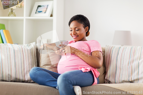 Image of happy pregnant woman with smartphone at home