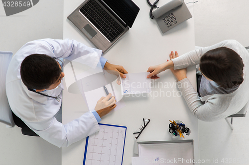 Image of doctor giving prescription to patient at hospital