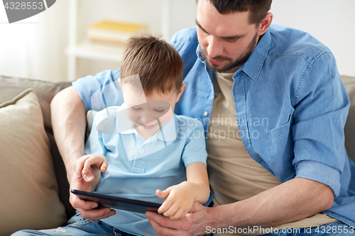 Image of father and son with tablet pc playing at home