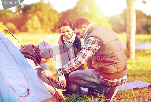 Image of happy family setting up tent outdoors