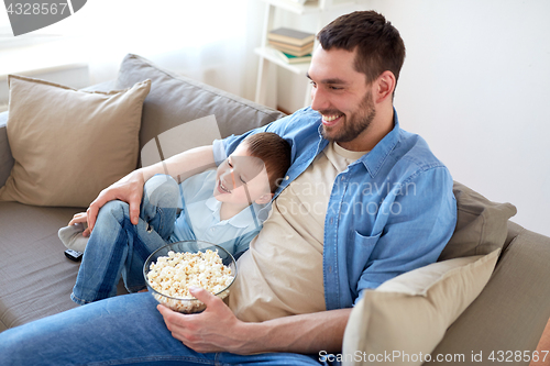 Image of father and son with popcorn watching tv at home