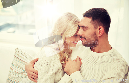 Image of happy couple covered with plaid on sofa at home