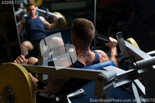 Image of man doing chest press on exercise machine in gym