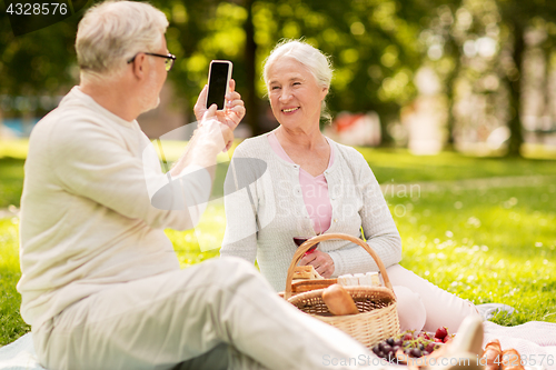Image of senior couple taking picture by smartphone at park