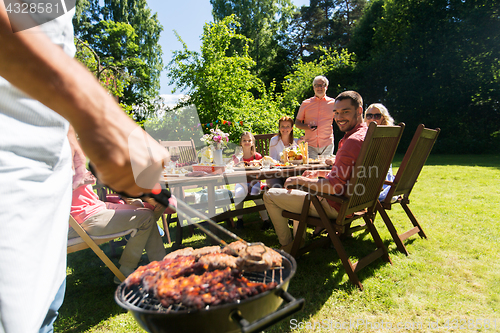 Image of man cooking meat on barbecue grill at summer party