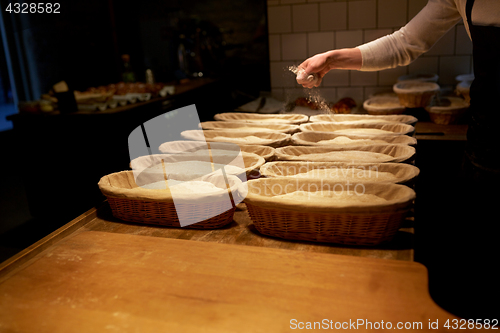 Image of baker with baskets for dough rising at bakery