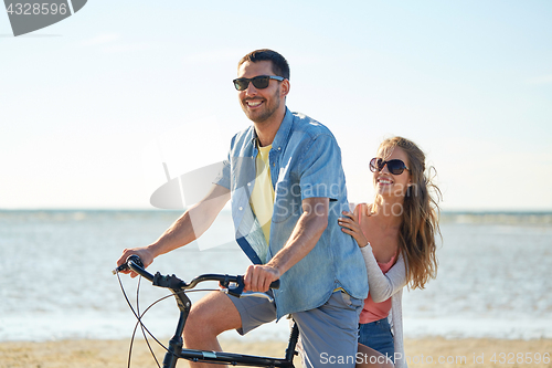 Image of happy young couple riding bicycle on beach