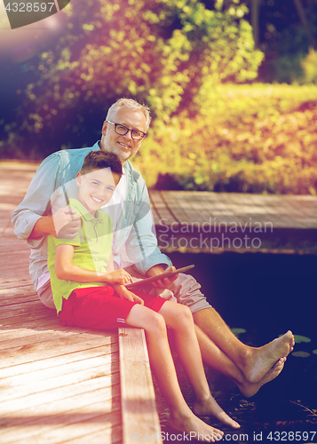 Image of grandfather and boy with tablet pc on river berth