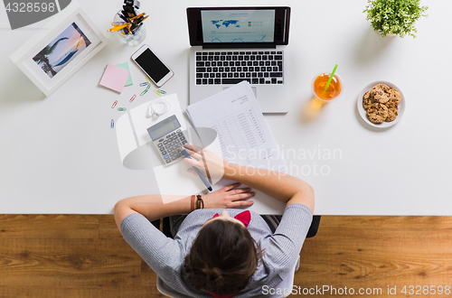 Image of woman with calculator and papers at office table