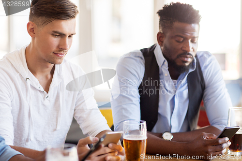 Image of male friends with smartphone drinking beer at bar