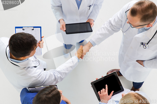 Image of doctors with tablet pc doing handshake at hospital