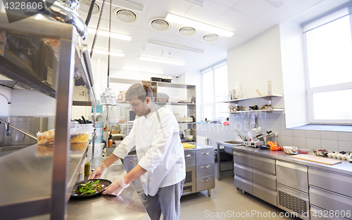 Image of happy male chef cooking food at restaurant kitchen