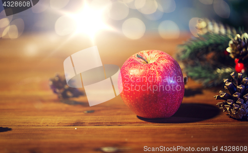Image of close up of apple with fir decoration on wood