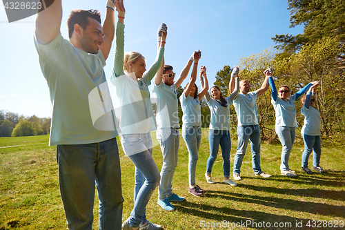 Image of group of happy volunteers holding hands outdoors