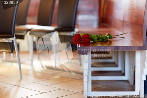 Image of red roses on bench at funeral in church