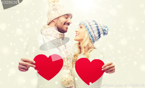 Image of smiling couple in winter clothes with red hearts