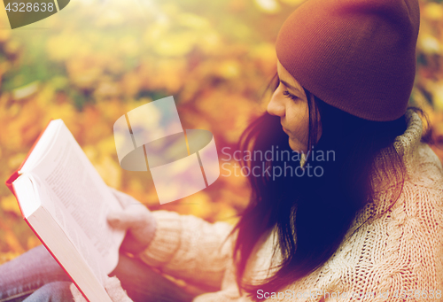 Image of close up of woman reading book in autumn park