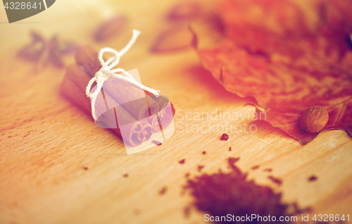 Image of cinnamon, maple leaf and almond on wooden board