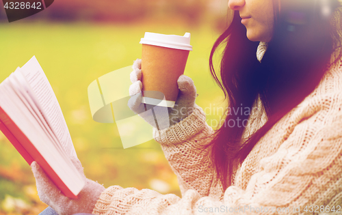 Image of woman with book drinking coffee in autumn park