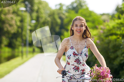 Image of happy woman riding fixie bicycle in summer park