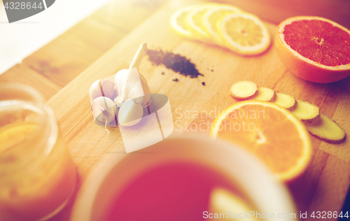 Image of ginger tea with honey, citrus and garlic on wood