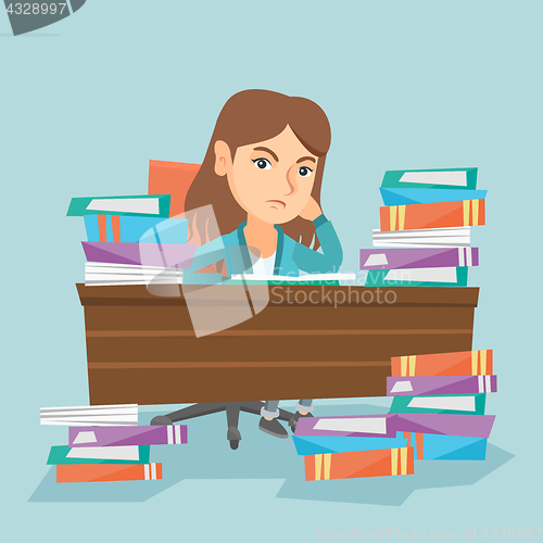 Image of Student sitting at the table with piles of books.