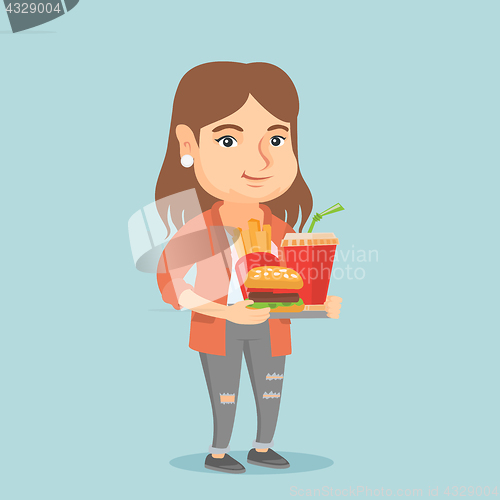 Image of Caucasian woman holding tray full of fast food.