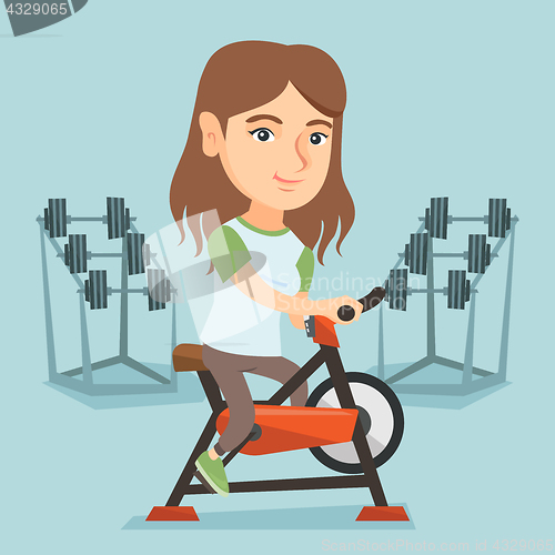 Image of Young caucasian woman riding stationary bicycle.