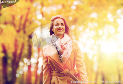 Image of beautiful happy young woman walking in autumn park