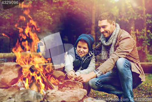 Image of father and son roasting marshmallow over campfire