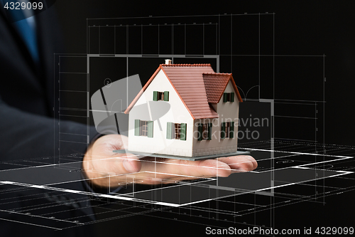 Image of close up of businessman hand holding house model