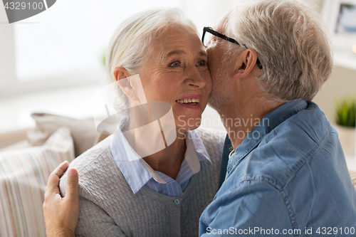 Image of happy senior couple hugging at home