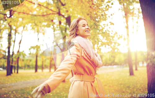 Image of beautiful happy young woman walking in autumn park