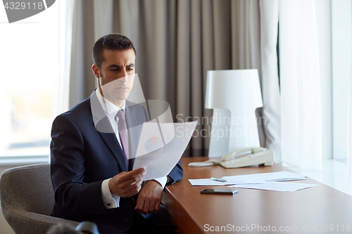 Image of businessman with papers working at hotel room