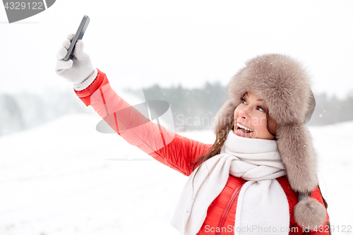 Image of happy woman taking selfie outdoors in winter