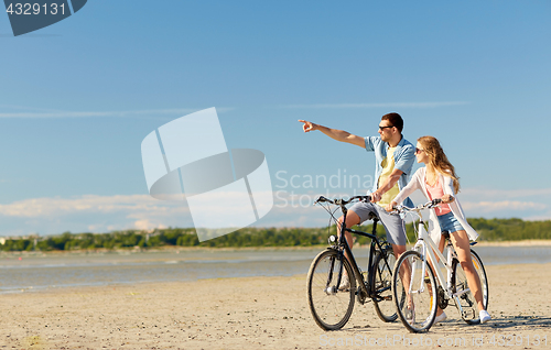 Image of happy young couple riding bicycles at seaside