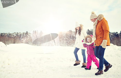 Image of happy family in winter clothes walking outdoors
