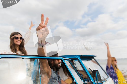 Image of hippie friends at minivan car showing peace sign