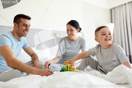 Image of happy family in bed at home or hotel room