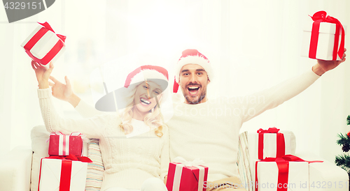 Image of happy couple at home with christmas gift boxes