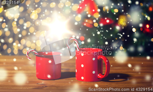 Image of christmas candy canes and cups on wooden table