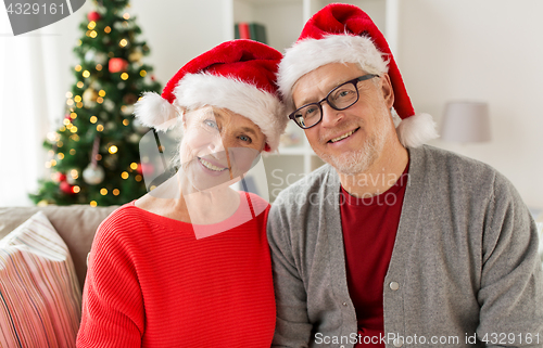 Image of happy senior couple in santa hats at christmas