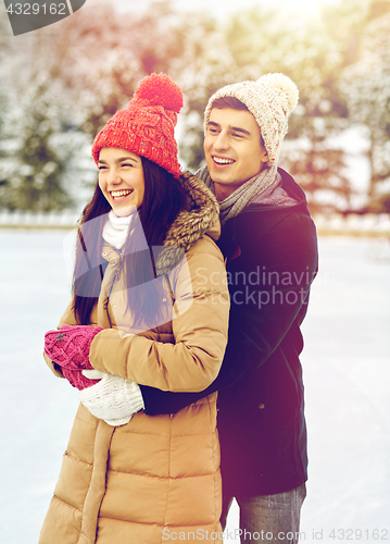 Image of happy couple ice skating on rink outdoors